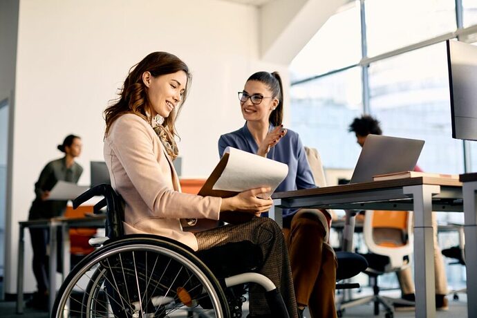 Peer experts in the workplace. Woman in a wheelchair assisting a client with obtaining support and disability services.
