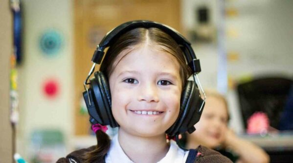 Smiling girl with autism noise canceling headphones